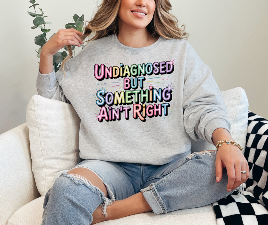Ash Gray Crewneck Shirt With A Graphic Text "Undiagnosed But Something Ain't Right"