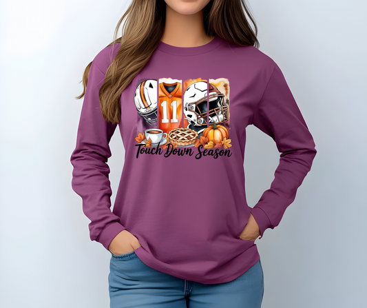 Berry colored long-sleeve  graphic t-shirt with football-themed design featuring a helmet, jersey, and pie with the words Touch Down Season 