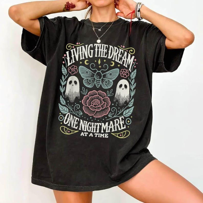 Graphic T-Shirt Apparel With A Ghost Graphic And athe Text Living The Dream One Nightmare At A Time